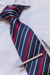 Businessman accessories. Man shirt with blue tie and silver tie clip close-up