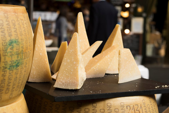 Parmesan is on the table for sale on the market. Parmigiano-Reggiano is made from unpasteurized cow's milk