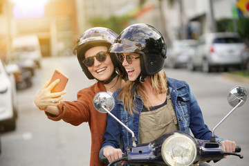 Happy young women taking a selfie on scooter in city