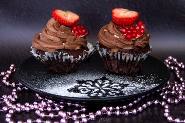 Chocolate cupcakes with berries on black plate.