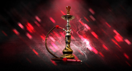 Hookah smoking on the background of a concrete floor, red blurred bokeh of the night city. Neon light smoke