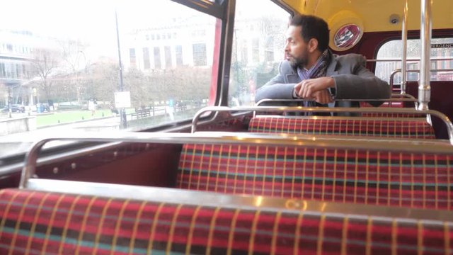 Man sits in an old London bus while travelling through the city