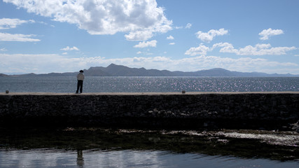 A Man watching the mountains silhouette across lake Titi Caca on island of Amantani, Peru