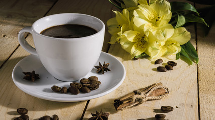 a cup of coffee and yellow flowers on wooden background