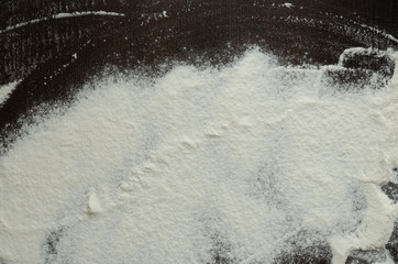 Texture of white flour on a dark wooden background.