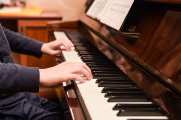 Girl's hands lie on the piano keys, the girl is preparing to play a popular musical composition