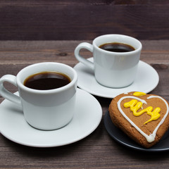 Two cups of coffee and heart cookies on a wooden table on Valentine's Day