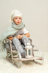 child with a lantern sitting in a sleigh