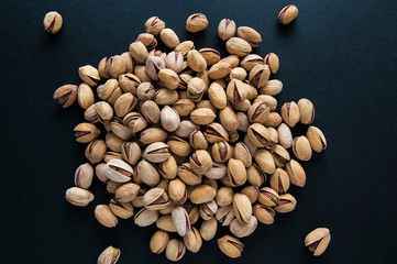 ripe pistachios on black background top view