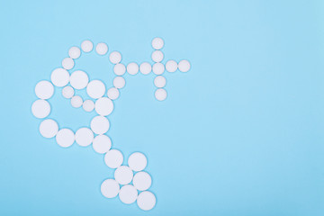 Concept of treatment of male and female genital disorders.Gender symbols of man and woman from white pills on blue background. Copy space for text.