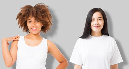 Asian and african american girl in blank template t shirt isolated on gray background. Women in tshirt with copy space and mock up for advertising. White shirts. Front view