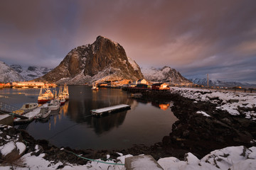 Hamnoy fishing village on Lofoten Islands at dawn. Norway with red rorbu houses in winter. A fishing boats at dawn in the fjord. Reine district