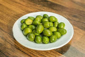 green olives in a bowl on a wooden table