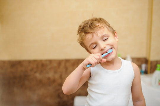 close up photo of a blond boy cleaning his teeth in a bathroom