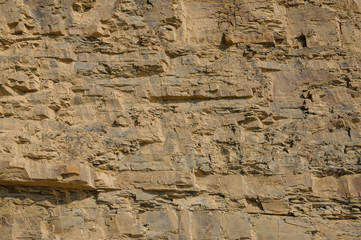 Texture of a yellow rock rock or background for design..Surface of the wall with textured surfaces for tiles.