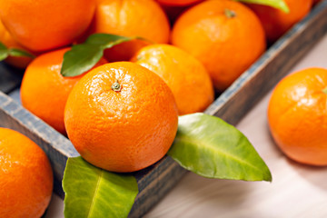 Fresh orange fruits with leaves on wooden table. Healthy food concept. Vitamin C