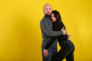 young sexy couple models in hugs in love smile and happy on yellow background , isolated on yellow , love ,couple 