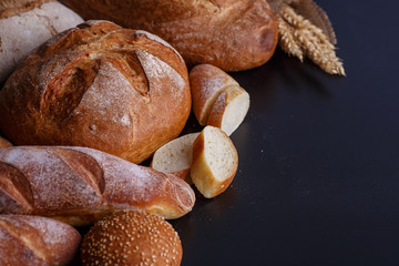 Bakery - gold rustic crusty loaves of bread and buns on black chalkboard background.