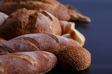 Bakery - gold rustic crusty loaves of bread and buns on black chalkboard background.