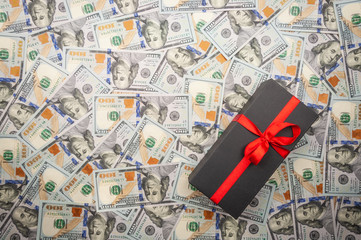 Black gift boxes with bow on background of dollars. top view, copy space