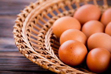 chicken eggs in a straw tray on an old wooden table