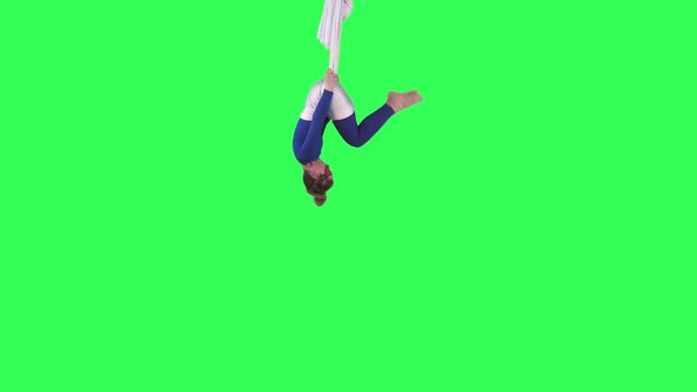 Acrobatic Aerial Yoga woman performs wearing a blue suit over a green screen