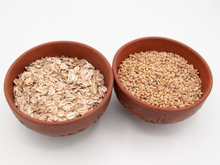 Uncoated brown ceramic bowls with oatmeal and wheat cereals isolated on a white background 