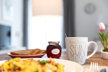 Am Morgen gedeckter Frühstückstisch mit frischen Rüheiern, Schinken und Kaffee in der Küche zubereitet