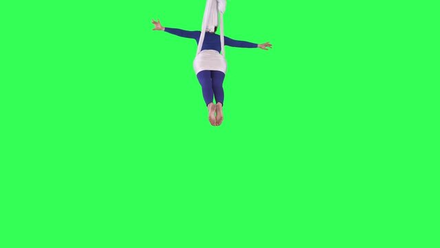 Acrobatic Aerial Yoga woman performs wearing a blue suit over a green screen