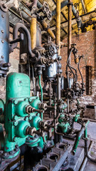 closeup of an old industrial machine with pipes with lot of valves and a brick wall
