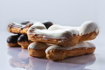 French dessert Eclair with white and black chocolate on white background. Closeup. Selective focus. High key.