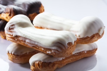 French dessert Eclair with white and black chocolate on white background. Closeup. Selective focus. High key.