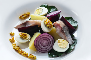 Salad from salty herring, beet, boiled potatoes, quail eggs and onions. With french mustard. High...