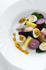 Salad from salty herring, beet, boiled potatoes, quail eggs and onions. With french mustard. High...