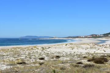 Beach with vegetation in sand dunes and lighthouse. Playa de Lariño, Carnota, Coruña Province, Spain.