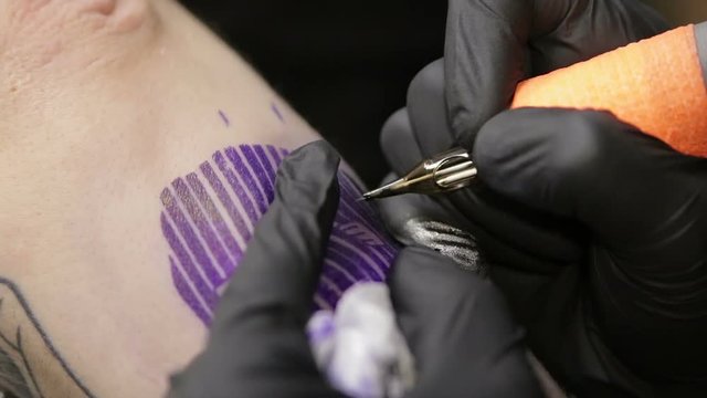 Tattoo artist fills tattoo on skin of client, macro view.