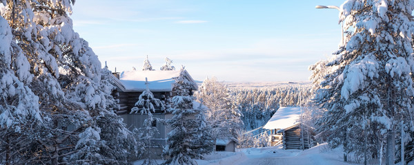 The Lapland winter landscape with wooden houses.  On the horizon a forest and a mountain. Morning and sunrise Finland Ruka.