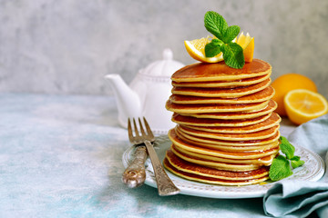 Stack of homemade lemon pancakes with honey and mint.