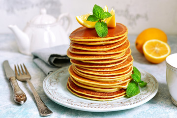 Stack of homemade lemon pancakes with honey and mint.