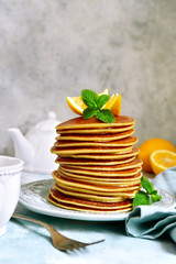 Stack of homemade lemon pancakes with honey and mint.