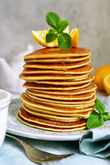 Stack of homemade lemon pancakes with honey and mint.