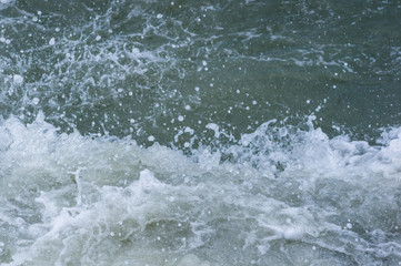 pebble stones on the sea beach, the rolling waves of the sea with foam