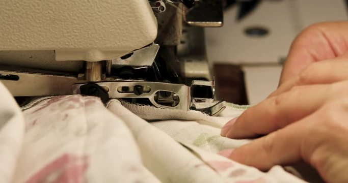Professional sewing machine overlock with white fabric close-up