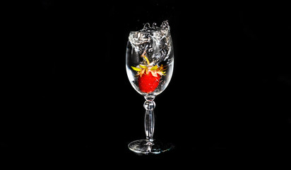 Strawberries fall in a glass of water