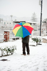man with colorful umbrella in snowy park.