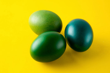 Green easter egg isolated on yellow background. Easter holiday concept. Stylish, colorful monochrome background with copy space.