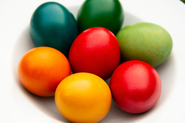 Easter eggs pile in white plate. Colorful, red, green ,blue, yellow and orange eggs. Top view.