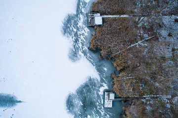 Aerial view of winter frozen lake with wooden houses on pier