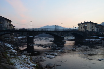 Fototapeta na wymiar Gray, winter arched bridge in the commune of Barghe