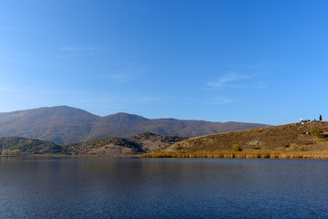 Fototapeta na wymiar Lake Zazari with a background of the mountains, greek flag and the big cross